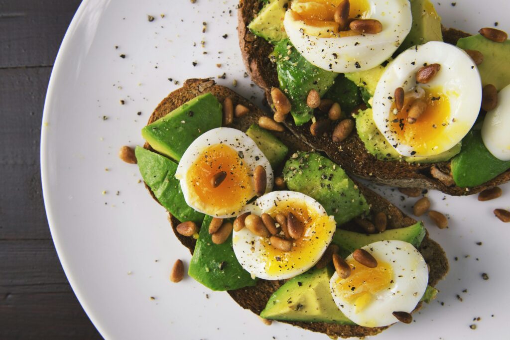 pexels-photo-566566-566566 Delicious avocado toast topped with soft-boiled eggs and pine nuts on a white plate.